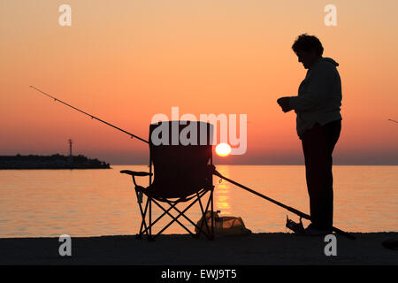 Frau in Silhouete bereitet Köder für den Fischfang. Myrina Stadt Sonnenuntergang. Lemnos / Insel Limnos, Griechenland / Hellas. Textfreiraum Stockfoto