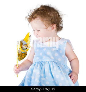 Kleines Mädchen in einem blauen Kleid mit einem Wind-Spielzeug spielen Stockfoto