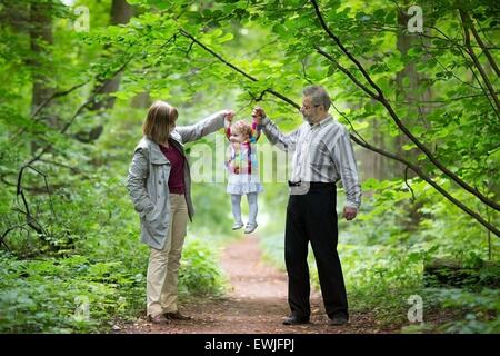 Junge Großeltern spielen mit ihrer Baby-Enkelin in ein Herbst Park Stockfoto