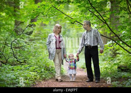 Junge Großeltern spielen mit ihrer Baby-Enkelin in ein Herbst Park Stockfoto