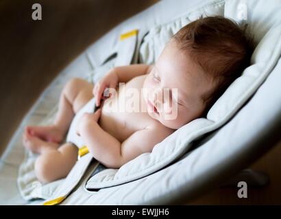 Süßes neugeborenes Mädchen schläft in einem Türsteher Stuhl in einem dunklen Raum Stockfoto