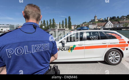 Schaffhausen, Schweiz. 26. Juni 2015. ILLUSTRATION - ein Polizeiauto wurde neben dem Rhein in Schaffhausen, Schweiz, 26. Juni 2015 geparkt. Ein Polizist steht neben dem Fahrzeug. Schaffhauser Wahrzeichen, Festung Munot, ist im Hintergrund abgebildet. Foto: Patrick Seeger/Dpa/Alamy Live News Stockfoto