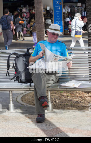 Manly, Australia-June 12 2015: sitzt ein Mann beim Lesen einer Zeitung auf dem Corso. Der Corso ist ein beliebter Ort, um zu sitzen Stockfoto