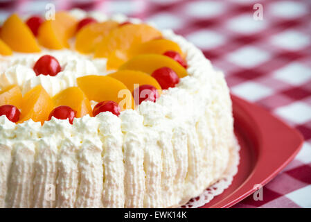 Hausgemachte Sahne-Torte mit Pfirsichen und Kirschen Stockfoto