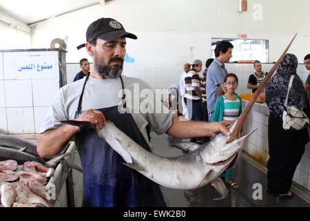 Tripoli, Libyen. 27. Juni 2015. Ein Fischhändler zeigt einen Fisch, während Einheimische Fisch vor Pause ihr Fasten am Fischmarkt im Zentrum von Tripolis, Libyen, am 27. Juni 2015 zu kaufen. Muslime auf der ganzen Welt absehen, Essen, trinken und Rauchen von Sonnenaufgang bis Sonnenuntergang während des Fastenmonats Ramadan. © Hamza Türkei/Xinhua/Alamy Live-Nachrichten Stockfoto