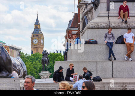 LONDON, UK - 15 Juni: Touristen sitzen auf den Stufen des Trafalgar Square, Big Ben im Hintergrund. 15. Juni 2015 in London Stockfoto