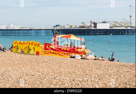 Strandwache am Strand in Brighton, East Sussex, UK mit Palace Pier (Brighton Pier) hinter sich, an einem Sommertag Stockfoto