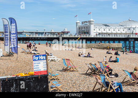 Urlauber entspannen Sie sich auf gemieteten gestreifte Liegestühle am Strand von Brighton an einem sonnigen Sommertag, Brighton, East Sussex, UK Stockfoto