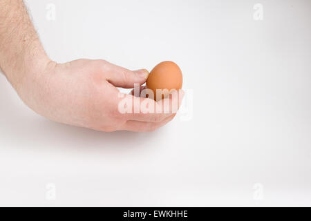 die menschliche Hand hält vertikal Ei auf weißem Hintergrund Stockfoto