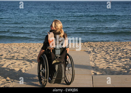 Frau in einem Rollstuhl auf einen Strand-Rampe Stockfoto