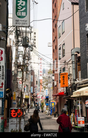 Typische japanische Stadt Straße. Schmale Straße zwischen zwei Reihen von Geschäften, Läden und Häuser mit Overhead Zeichen, Kabel und Drähte durcheinandergeworfen. Stockfoto