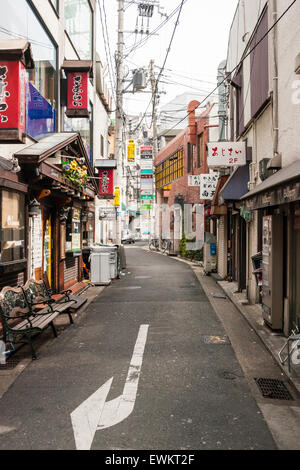 Typische japanische Stadt Straße. Schmale Straße zwischen zwei Reihen von Geschäften, Läden und Häuser mit Overhead Zeichen, Kabel und Drähte durcheinandergeworfen. Stockfoto