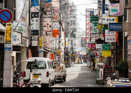 Typische japanische Stadt Straße. Schmale Straße zwischen zwei Reihen von Geschäften, Läden und Häuser mit Overhead Zeichen, Kabel und Drähte durcheinandergeworfen. Stockfoto