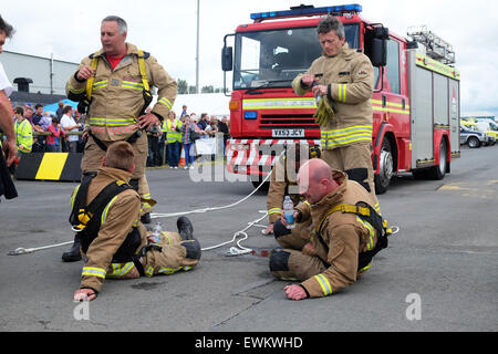 Shobdon, Herefordshire, England. 28. Juni 2015. Feuerwehrleute von Kingsland, Herefordshire Zusammenbruch mit Erschöpfung nach dem ziehen ein Feuerwehrauto gegen die Uhr auf dem Shobdon Food Festival in einem Wettbewerb mit einem Team von Presteigne, Powys, Wales 200 Metern Länge. Das Feuerwehr-Team von Kingsland gewann das Rennen. Die Veranstaltung fand am Shobdon Flugplatz. Stockfoto