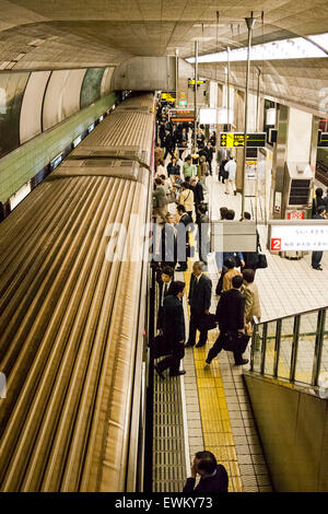 Innenraum der japanischen U-Bahn Station in Osaka. Ansicht von oben der Menschen auf der Plattform mit Zug, während die Passagiere ein- und aussteigen. Stockfoto