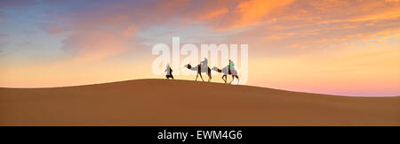 Touristen auf Kamel reiten bei Sonnenuntergang, Erg Chebbi Wüste bei Merzouga, Sahara, Marokko Stockfoto