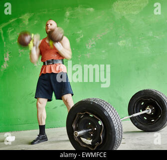 Gewichtheben, sportlicher Mann und tägliches Training im Inneren der Gebäudes aus Beton, vorsätzliche Bewegungsunschärfe Stockfoto