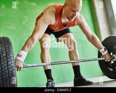 Gewichtheben, sportlicher Mann und tägliches Training im Inneren der Gebäudes aus Beton Stockfoto