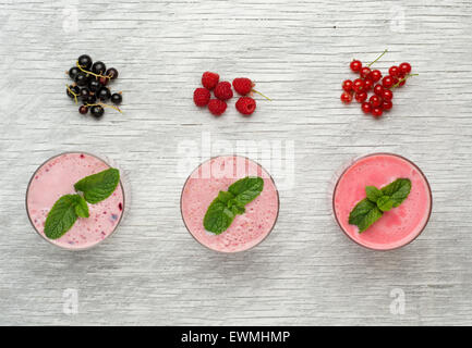 Frische Milch, Johannisbeere, Himbeere und rote Johannisbeere Getränke auf Wodeen Tisch, verschiedene Protein-Cocktails mit frischen Früchten Stockfoto