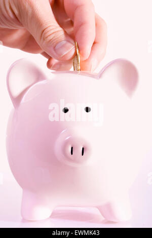 Stock Bild des Mannes, die Hinterlegung einer Münze in ein Sparschwein Stockfoto