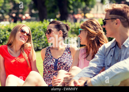 Gruppe von lächelnden Freunde draußen sitzen im park Stockfoto