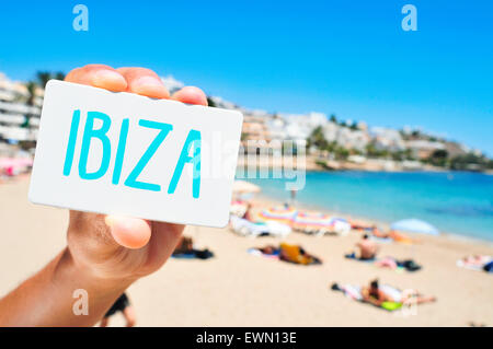 Nahaufnahme der Hand von einem kaukasischen Jüngling zeigt ein Schild mit dem Wort Ibiza, geschrieben, in den Strand von Ses Figueretes in Stockfoto