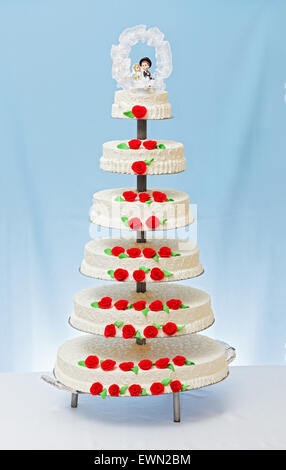 Mehrstöckige Weiße Hochzeitstorte mit roten rose Marzipan Dekoration und Topper an der Spitze Stockfoto