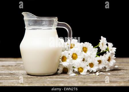 Milch und Blumen auf einem hölzernen Hintergrund Stockfoto