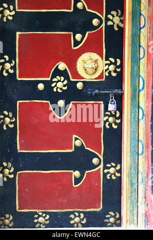 Rot und schwarz lackiert-traditionellen tibetischen Stil-Holztür mit vergoldetem Messing Türknopf alten Viertel der Stadt. Gyantse-Tibet. Stockfoto