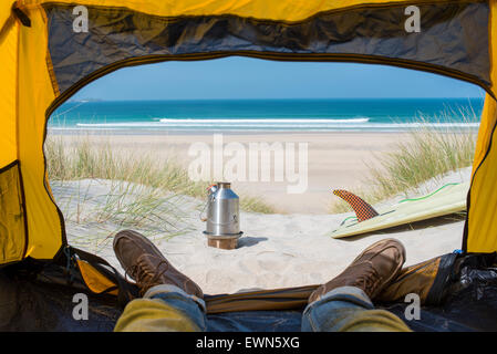 Blick von einem Zelt am Strand mit einem Surfbrett, Herd und das Meer in der Ferne. Stockfoto