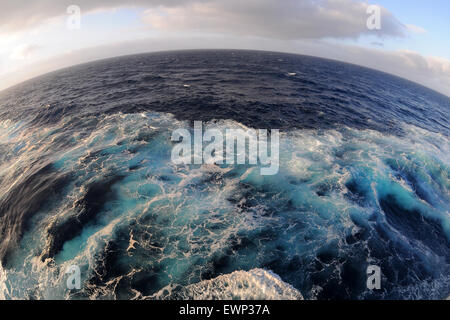 Ein Fisch Auge Blick auf blauen Wellen im Meer bei Sonnenuntergang von der Seite eines Kreuzfahrtschiffes. Stockfoto