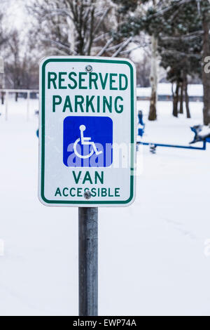 Einen behinderten Parkplatz Schild vor dem Schnee bedeckt Spielplatz in Bethanien, Oklahoma, USA. Stockfoto