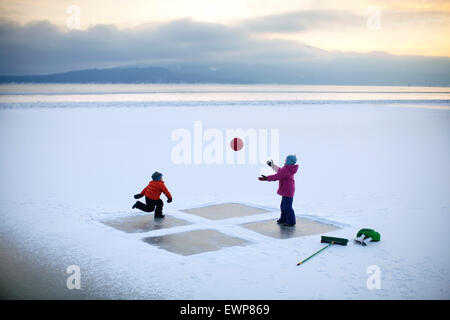 6 Jahre, junge und Mädchen, Alter 10 ein Spiel von vier Quadrat auf einem zugefrorenen See mitten im Winter. Stockfoto