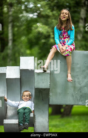 Mädchen mit ihren kleinen Bruder auf dem Spielplatz im City Park. Stockfoto