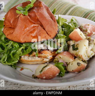 Lachs-Burger mit Rucola und Kartoffelsalat Stockfoto