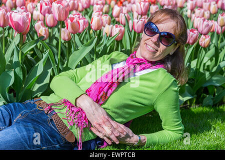 Kaukasische Frau liegend vor rosa Tulpenfeld Stockfoto