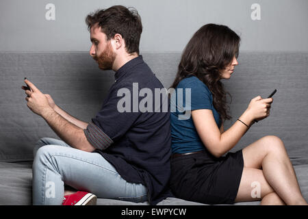 Junge Stille paar mit Smartphones, die auf einer Couch sitzend Stockfoto