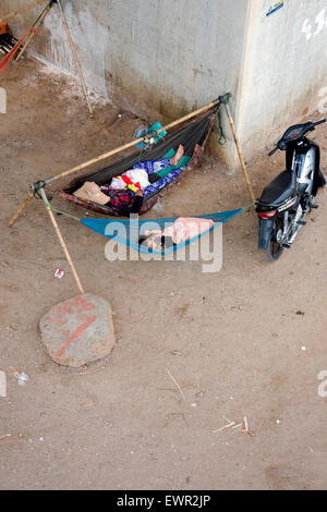 Eine Frau und ein Kind schlafen in Hängematten unter einer Brücke in Kampong Cham, Kambodscha. Stockfoto