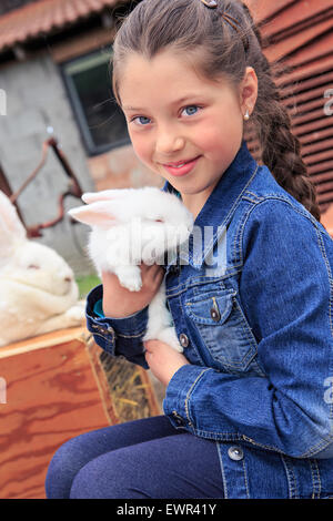 kleines Mädchen mit einem Kaninchen vor dem Bauernhof Stockfoto