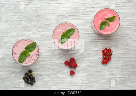 Frische Milch, Johannisbeere, Himbeere und rote Johannisbeere Getränke auf Wodeen Tisch, verschiedene Protein-Cocktails mit frischen Früchten Stockfoto