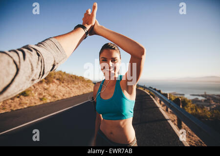 First-Person-Ansicht von Mann und Frau ein high Five zu tun. Glückliche junge Frau geben hohe fünf man nach outdoor-Training. Stockfoto