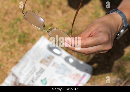 Frau hält Gläser auf dem Hintergrund der Zeitung Stockfoto