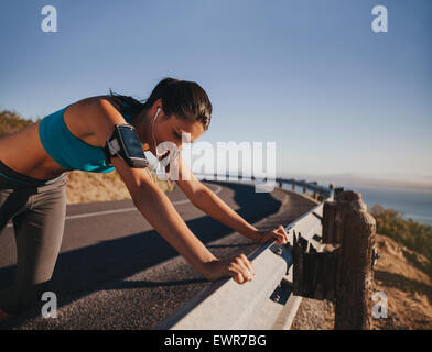 Müde Läufer eine Pause an Land Straße Leitplanke gelehnt. Passen Sie die junge Frau Athlet Training im Freien. Stockfoto