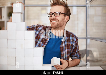 Junge Manager in Brillen Bau Papier Pyramide Stockfoto