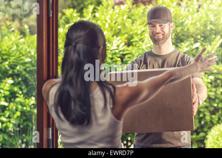 Übernahme eines großen Grundstücks hält seine Arme, der freundlich lächelnden Bote, wie er es, Blick vom übergibt Frau Stockfoto