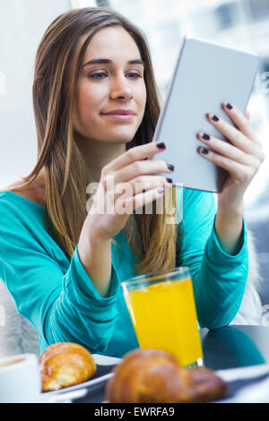 Fröhliche elegante Frau mit Tablet beim Frühstück im Café Stockfoto