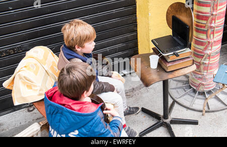 Alte, gebrauchte Bücher verwendet als Unterstützung für Laptop, Gegenüberstellung, wie diese jungen Film ansehen. Bei Marken, Jules Valles, Clingancourt, Flohmarkt, Paris, Frankreich. Humor Stockfoto