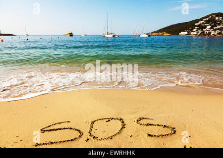 SOS sparen unsere Seelen Wort in Sand geschrieben am Strand Rettung Insel Schiffbruch verloren allein Spanisch See Küste Küsten Resort Stockfoto