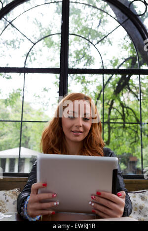 Hübsches Mädchen posiert mit einer Tablette im café Stockfoto