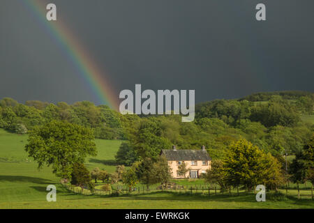 Regenbogen und schwarzen Himmel, Himmel während starkem Regendusche über ein Landhaus, Residenz in der Nähe von Llanfair Caereinion,Powys,Wales,U.K. Stockfoto